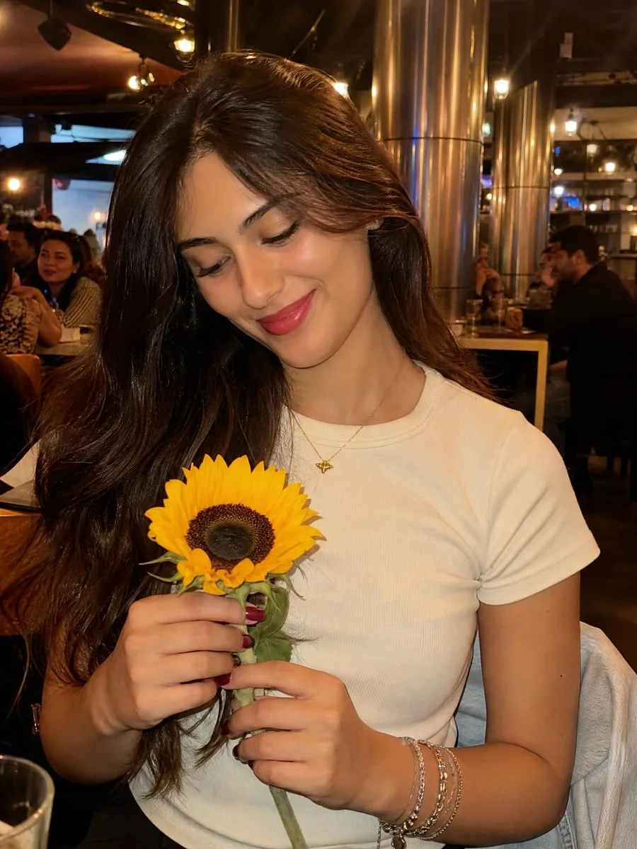 Woman with Sunflower in Warm Restaurant Setting reference