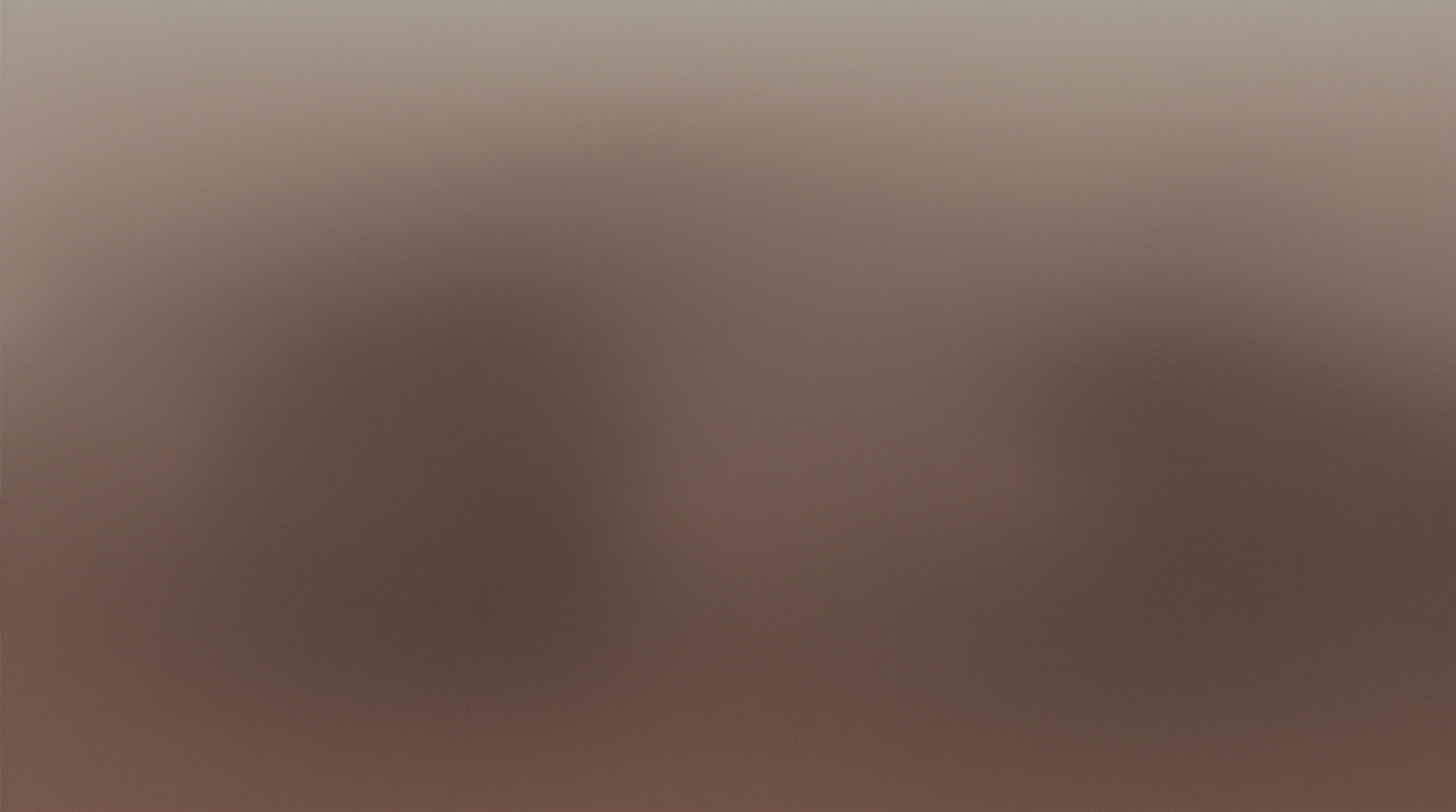 ソファに並んで座るカップルを背後から捉えた構図。それぞれが親の写真を表示したスマートフォンを持ち、目の前のノートパソコンの画面に柔らかなパステル調のAI赤ちゃんプレビューが映る、暖かな午後の光に包まれたシーン。